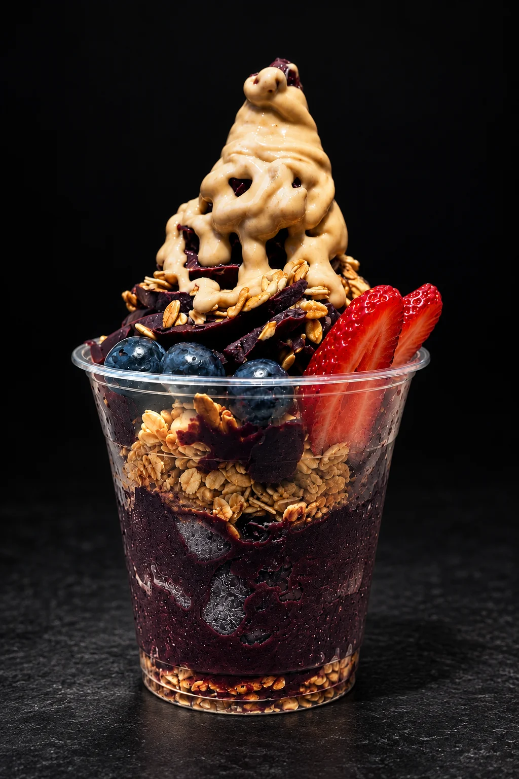 A Nabil's açaí cup with granola, blueberries and strawberries under a thick drizzle